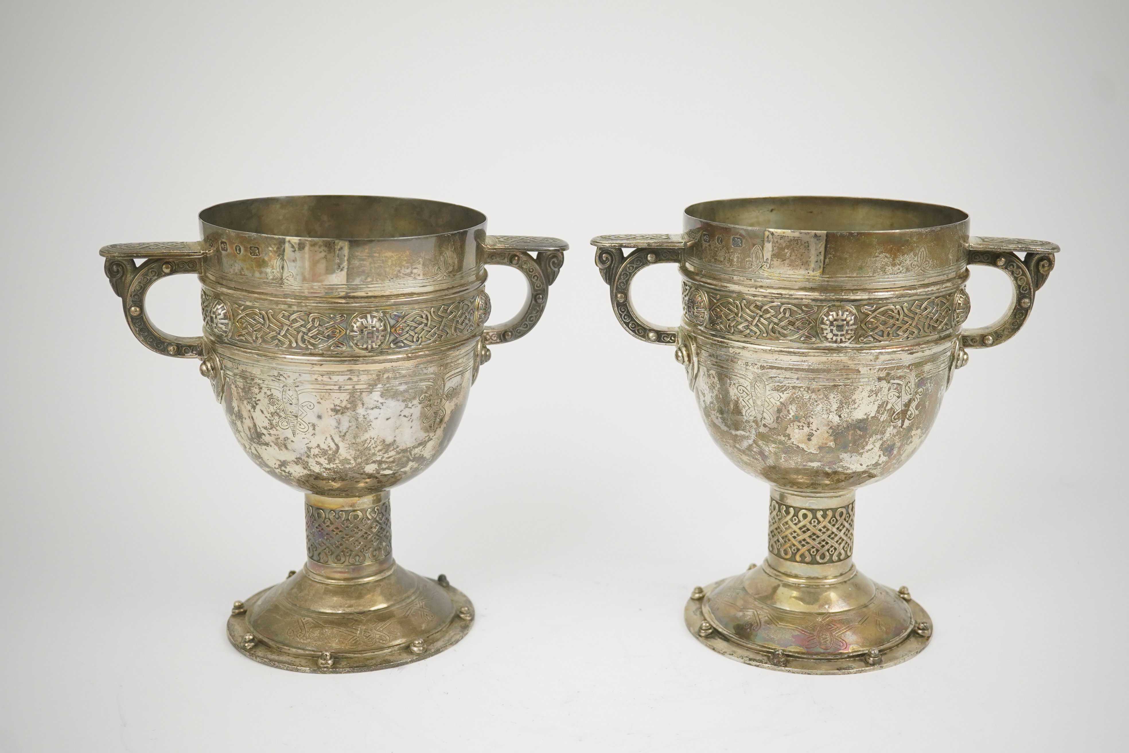 A pair of late Victorian Arts & Crafts Celtic style silver two handled presentation pedestal trophy cups, by Elkington & Co